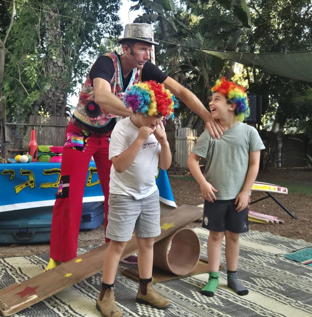 מפעיל יום הולדת ג'אגלינג מלביש ילדים בפאות ליצן צבעוניות